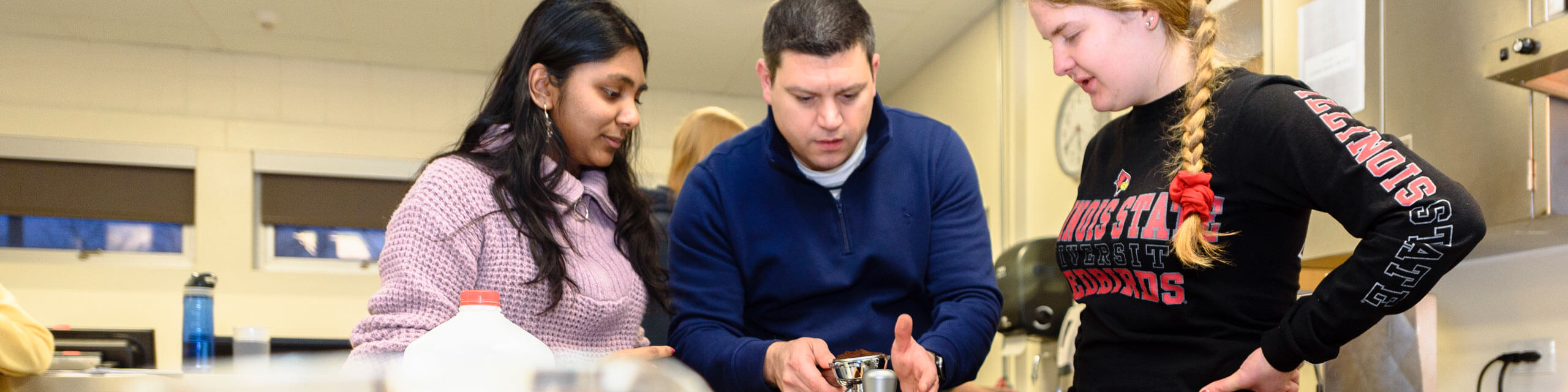 Three people engaged in an activity around a table in a classroom lab.